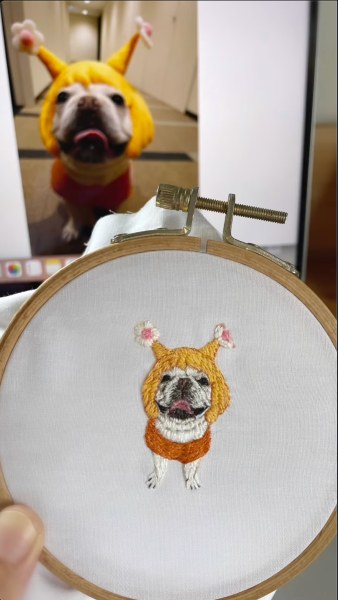 刺繍枠の中のかぶり物姿のフレンチブルドッグ
